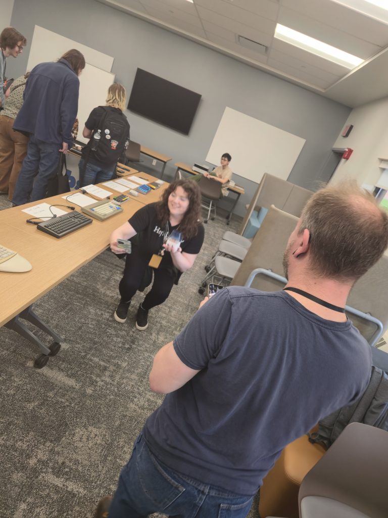 A picture of a man taking a picture of a woman taking a selfie of herself holding a NovelKeys big blue clicky switch