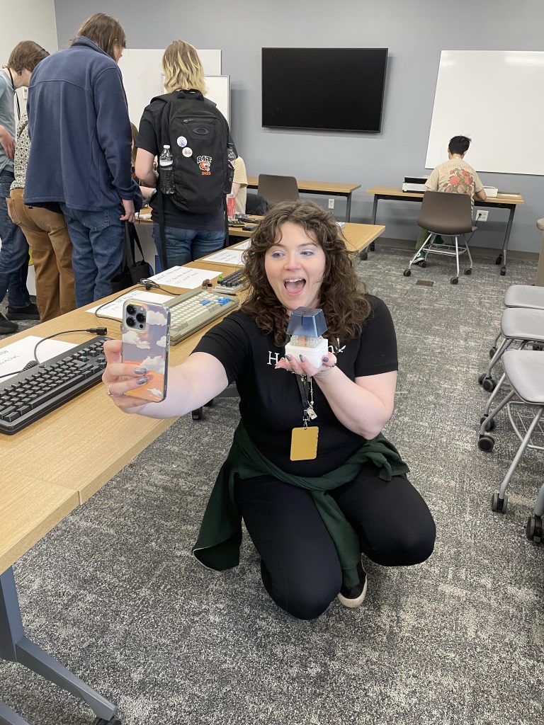 A picture of a woman taking a selfie of herself holding a NovelKeys big blue clicky switch